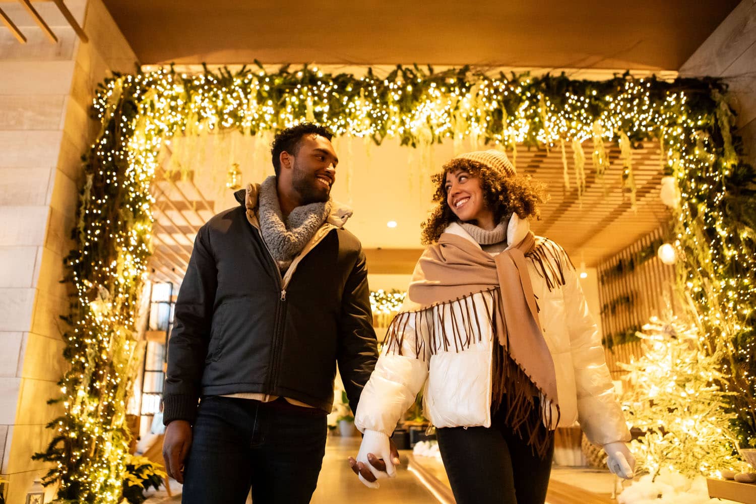 A hotel lobby with two guests walking inside a holiday themed hallway