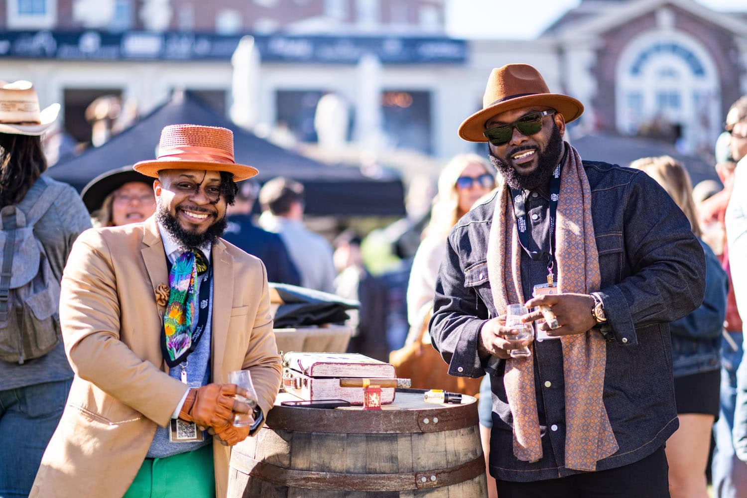 Two men sipping bourbon and holding cigars outside