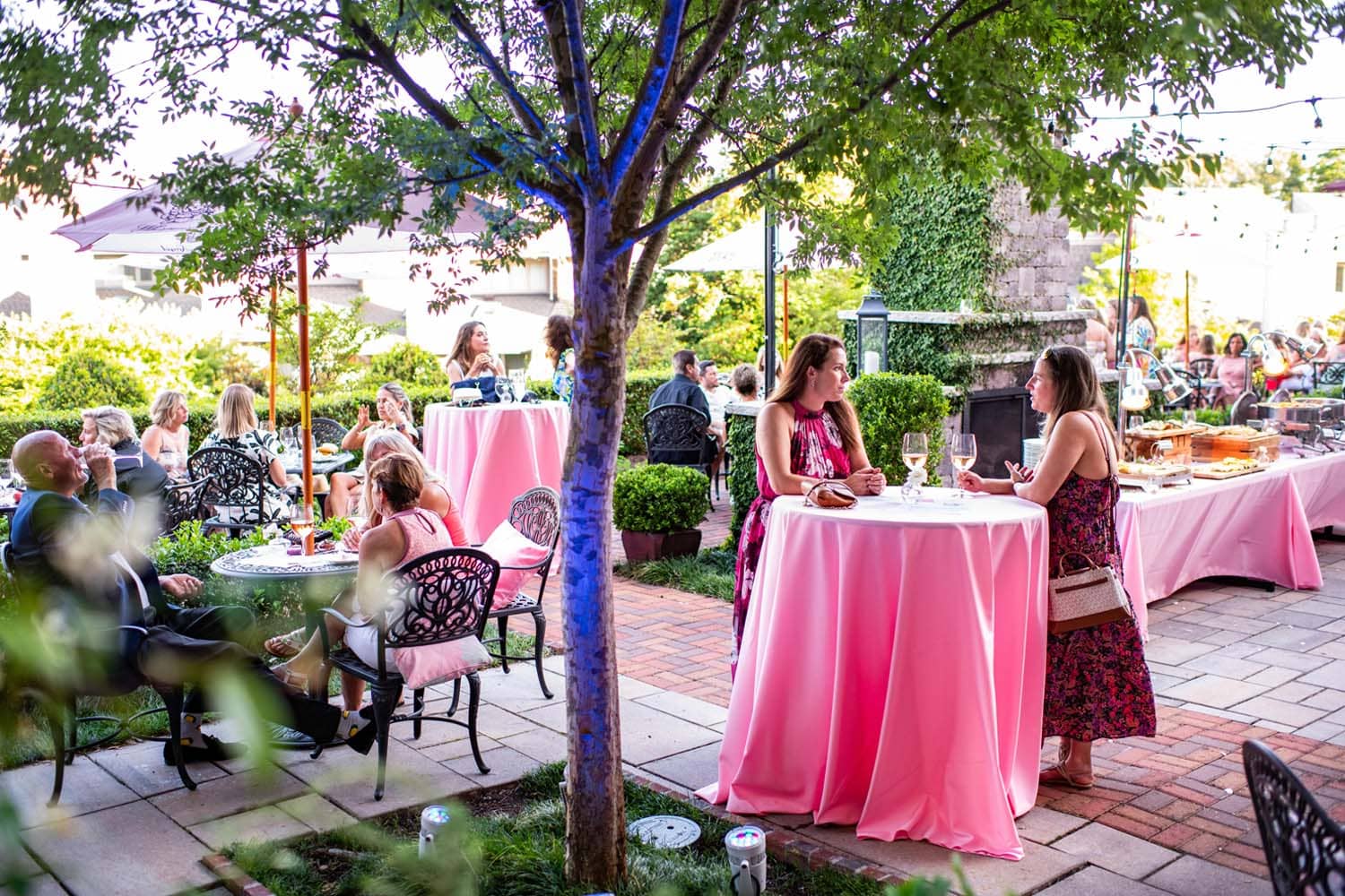 A neatly decorated table filled with rose wine at an outdoor garden event