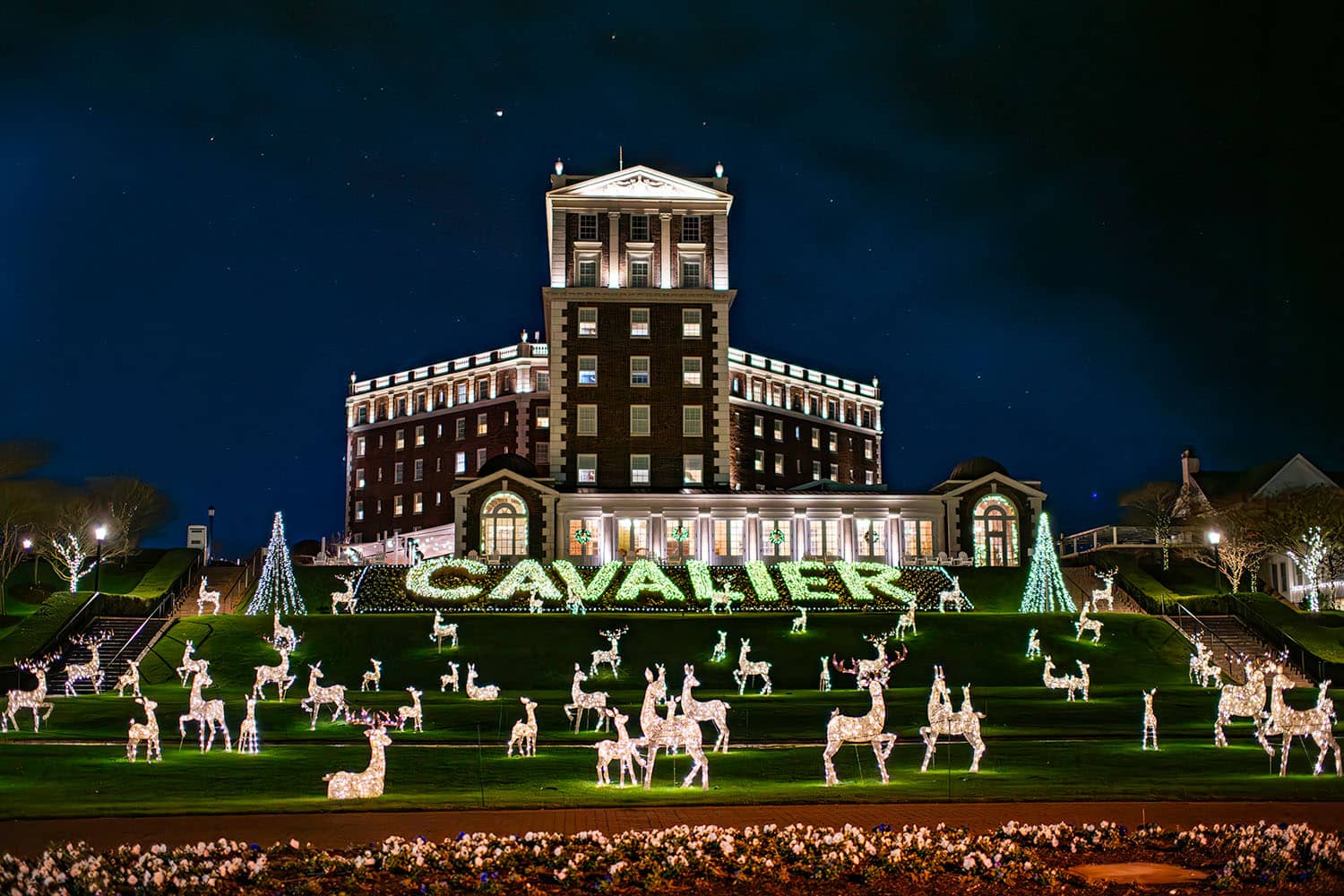 The entrance to The Historic Cavalier Hotel during the holiday season with white lights and decorations