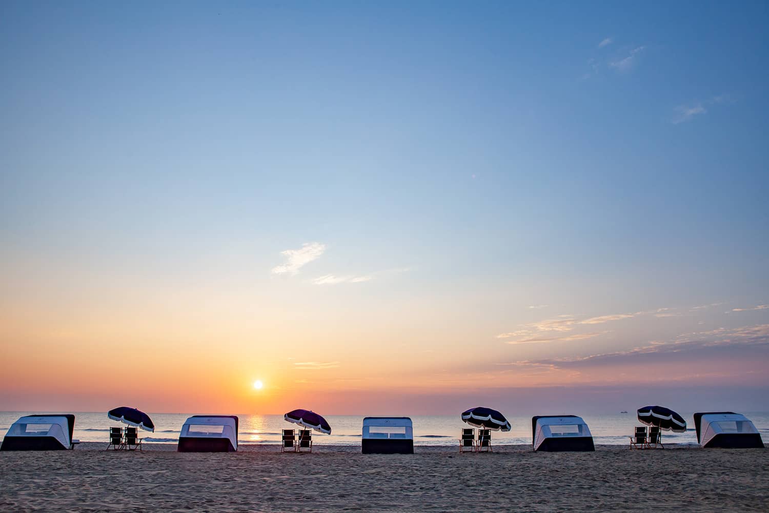An empty beach with chairs and towels at sunset