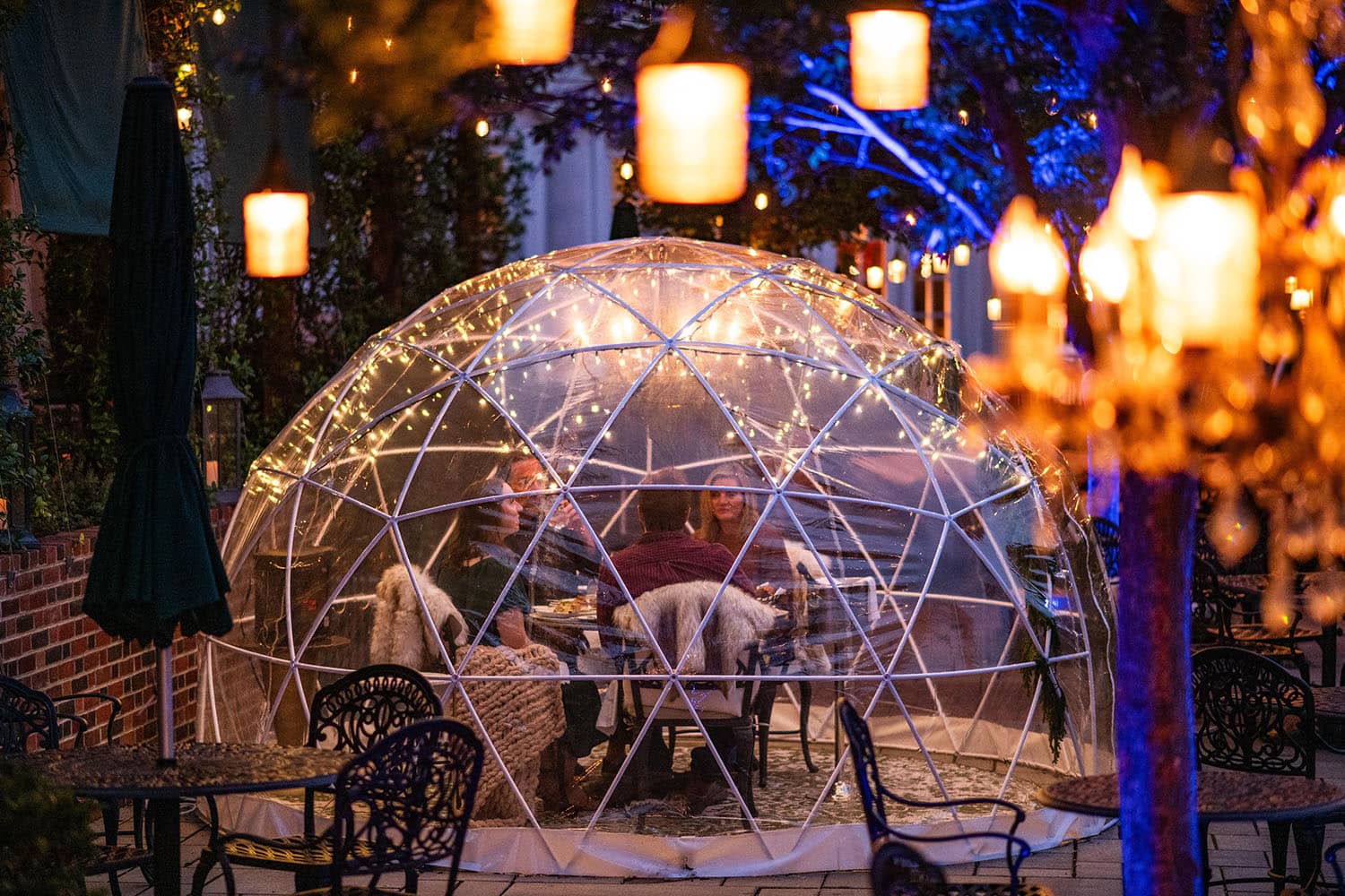 An outdoor igloo with four people dining inside of it