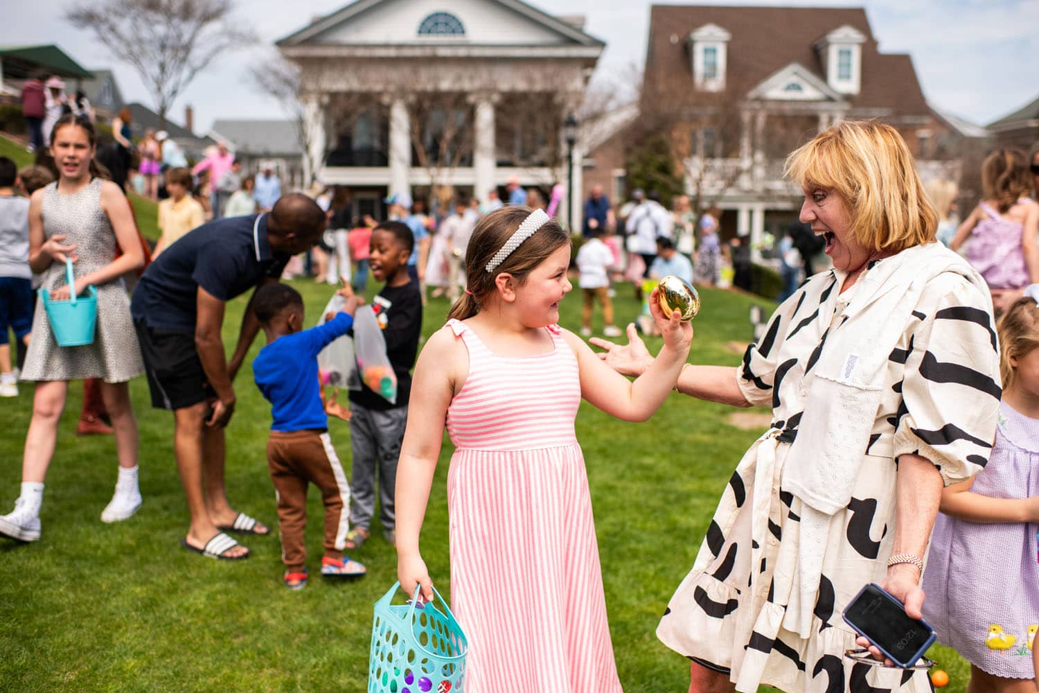 A grandmother and her granddaughter searching for Easter Eggs on a lawn