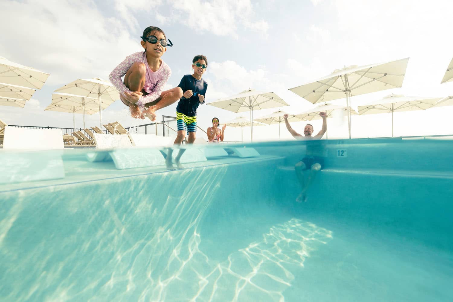 Children swimming in a pool next to their parents