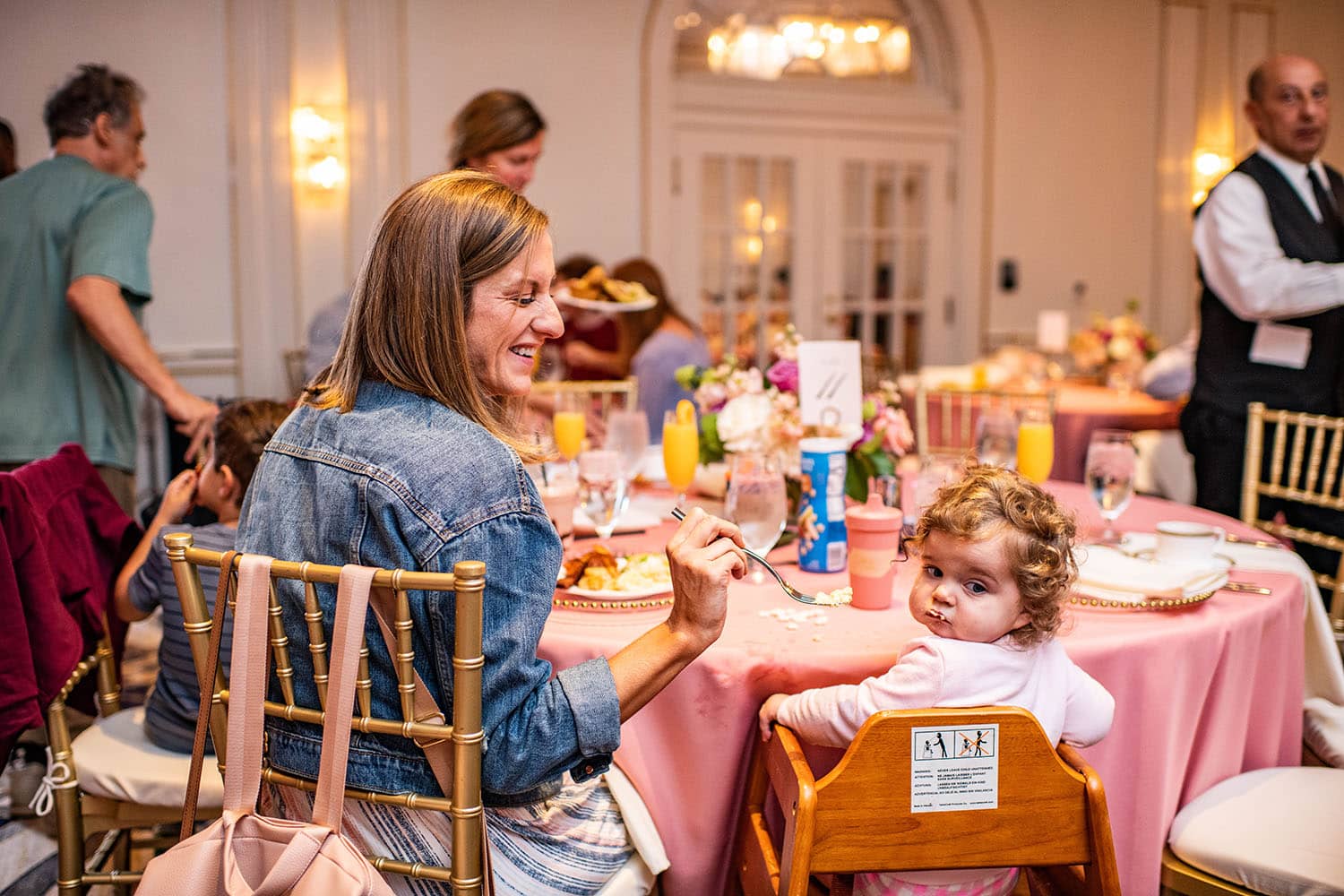 A mother feeding her young child food in a highchair