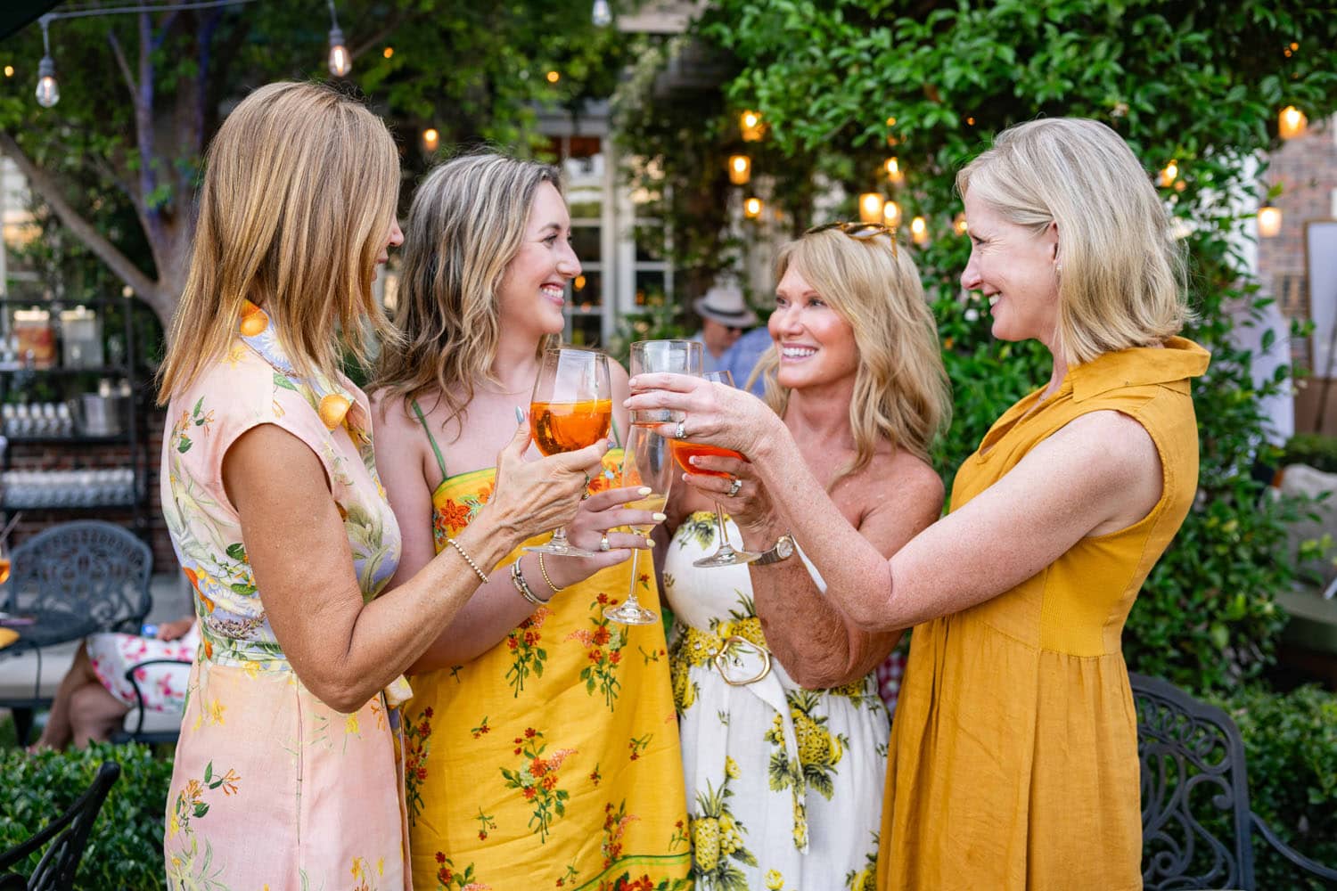 A group of four women enjoying drinks outside a garden party
