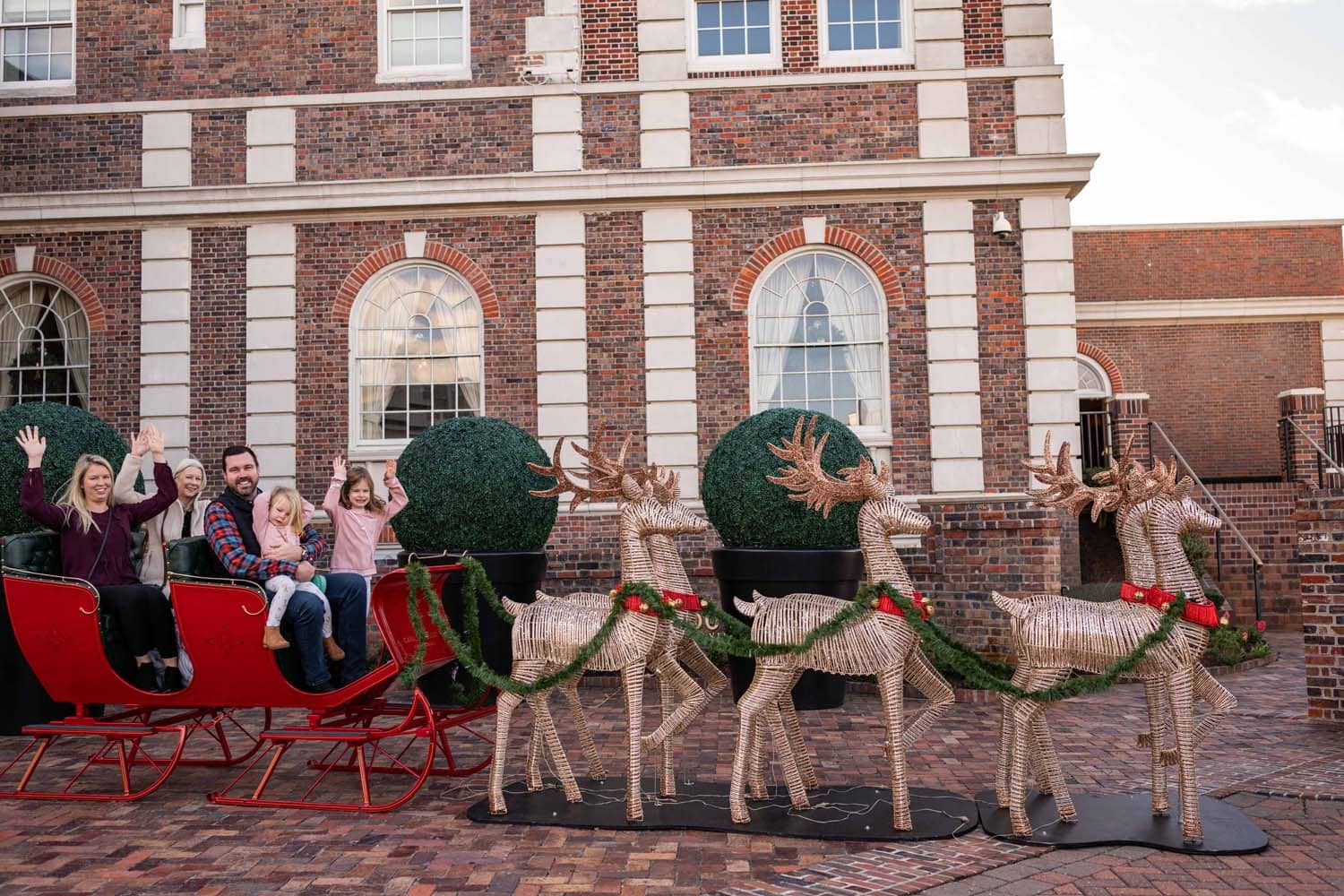 A family sitting in Santa's sleigh outside The Historic Cavalier Hotel