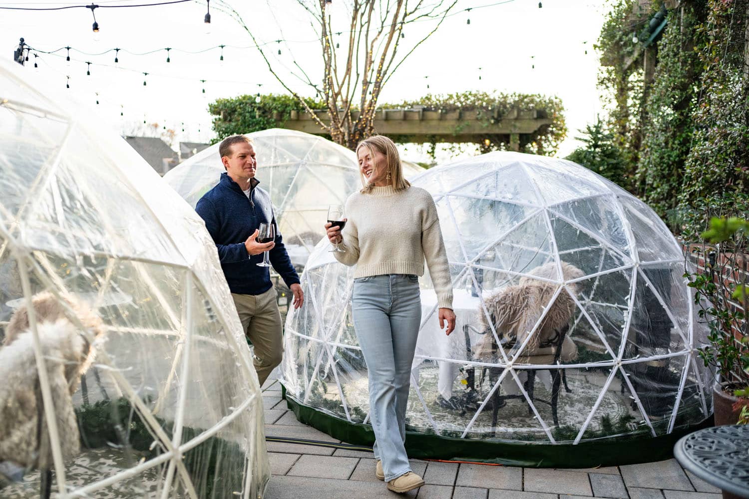 A couple walking outside next to heated igloos