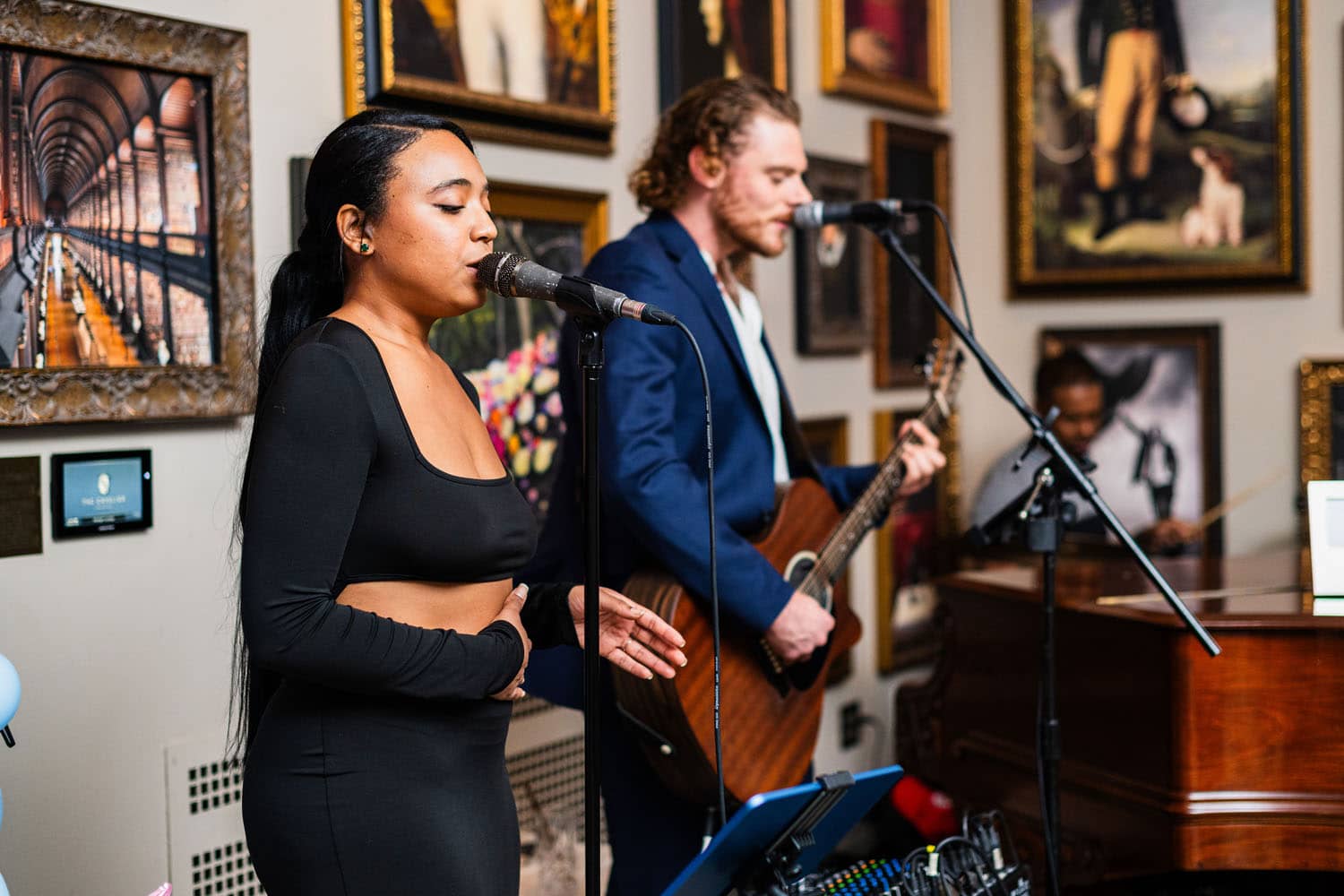 An artist singing in front of a microphone inside The Raleigh Room
