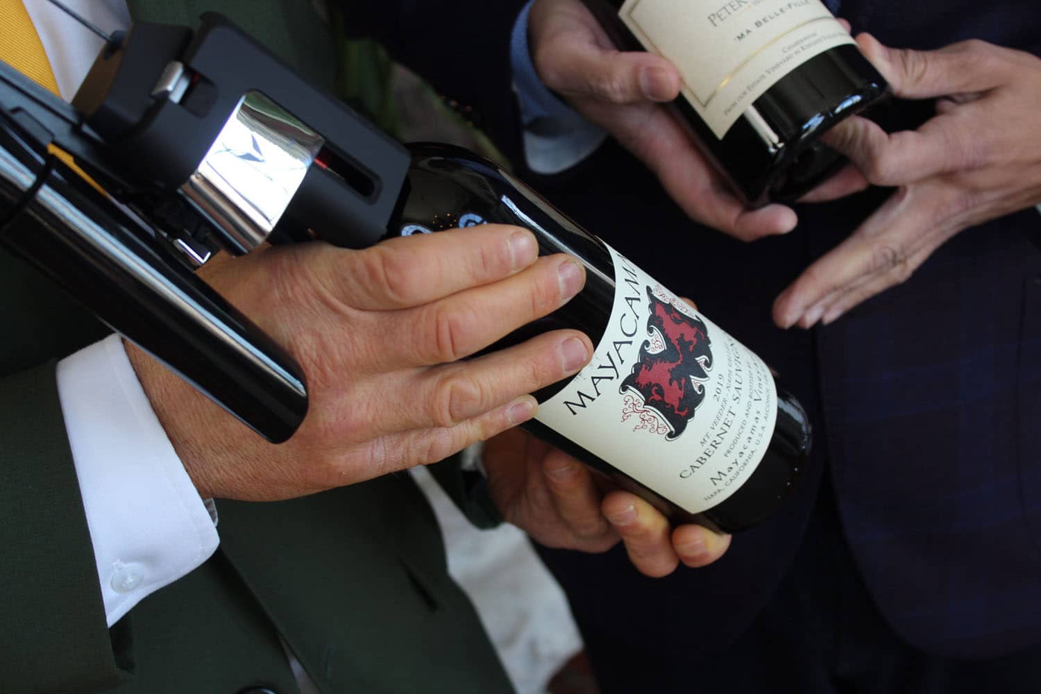 Two bottles of wine being held by sommeliers