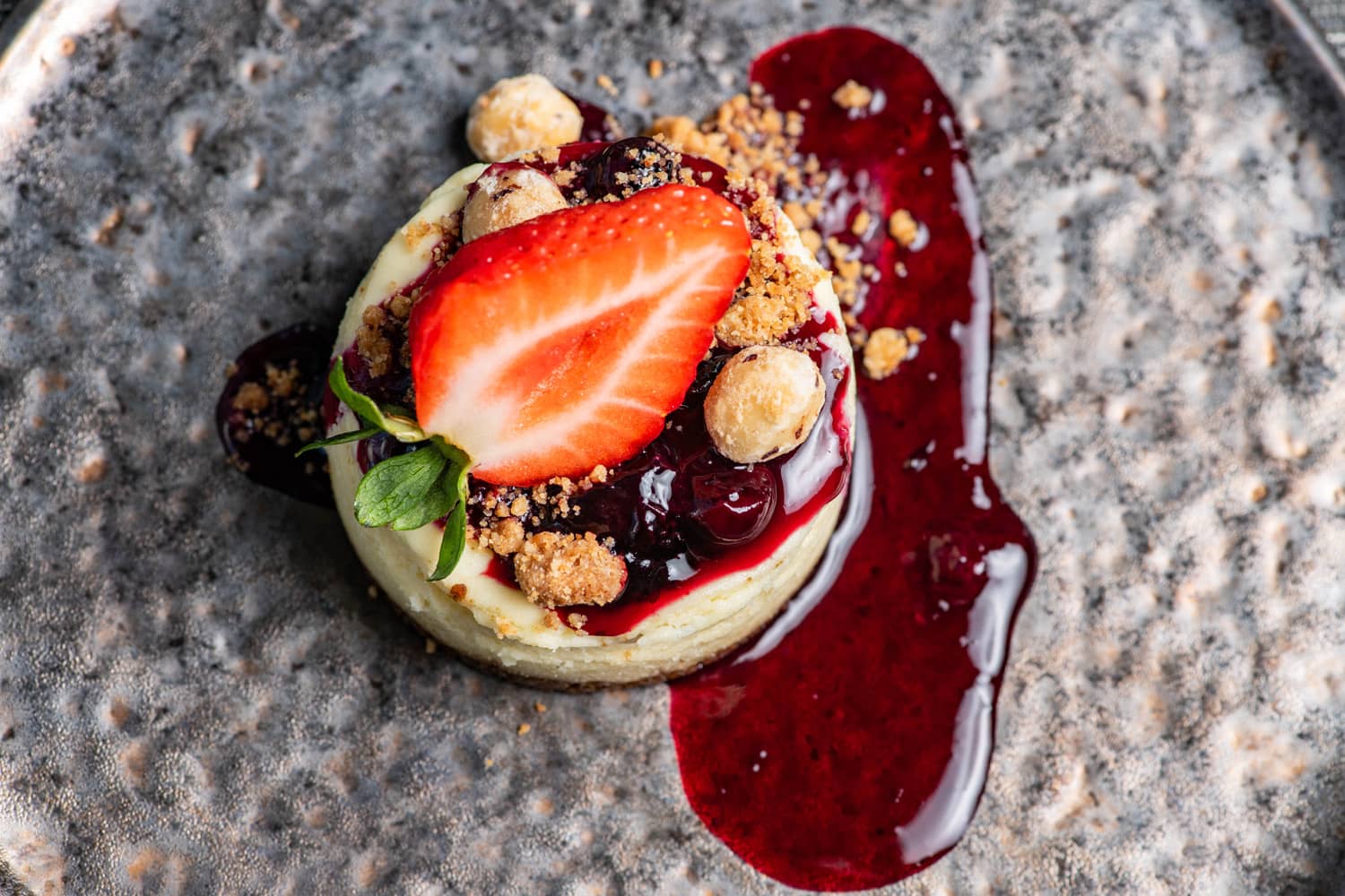 Berry cheesecake topped with fresh strawberries, blueberries, hazelnuts, and sauce at Tulu Seaside Bar & Grill
